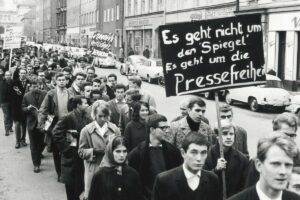 In_München_demonstrierten_am_02.11.1962_Studenten_gegen_die_jüngsten_Polizei-Maßnahmen_in_der_Hamburger_Spiegel-Redaktion._Etwa_300_Teilnehmer_maschierten_mit_Spruchtafeln_von_der_Universität_zum_Königsplatz,_wo_ein_Sprecher_die_Forderung_der_Studenten_nach_Pressefreiheit_unterstrich._Im_Zuge_der_Spiegel-Affäre_mussten_sich_Mitarbeiter_des_Nachrichtenmagazins_Spiegel_wegen_eines_kritischen_Artikels_gegen_eine_Anklage_des_Landesverrats_zur_Wehr_setzen.