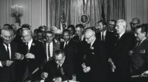 The_Civil_Rights_Act_of_1964_is_a_landmark_piece_of_civil_rights_legislation_in_the_United_States_that_outlawed_discrimination_based_on_race,_color,_religion,_sex,_or_national_origin._It_ended_unequal_application_of_voter_registration_requirements_and_racial_segregation_in_schools,_at_the_workplace_and_by_facilities_that_served_the_general_public._Powers_given_to_enforce_the_act_were_initially_weak,_but_were_supplemented_during_later_years._Congress_asserted_its_authority_to_legislate_under_several_different_parts_of_the_United_States_Constitution,_principally_its_power_to_regulate_interstate_commerce_under_Article_One_(section_8),_its_duty_to_guarantee_all_citizens_equal_protection_of_the_laws_under_the_Fourteenth_Amendment_and_its_duty_to_protect_voting_rights_under_the_Fifteenth_Amendment._The_Act_was_signed_into_law_by_President_Johnson_on_July_2,_1964,_at_the_White_House._Photographed_by_Cecil_Stoughton.