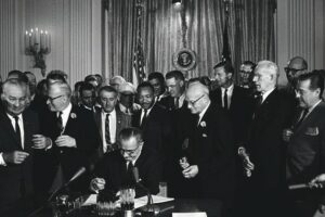 The_Civil_Rights_Act_of_1964_is_a_landmark_piece_of_civil_rights_legislation_in_the_United_States_that_outlawed_discrimination_based_on_race,_color,_religion,_sex,_or_national_origin._It_ended_unequal_application_of_voter_registration_requirements_and_racial_segregation_in_schools,_at_the_workplace_and_by_facilities_that_served_the_general_public._Powers_given_to_enforce_the_act_were_initially_weak,_but_were_supplemented_during_later_years._Congress_asserted_its_authority_to_legislate_under_several_different_parts_of_the_United_States_Constitution,_principally_its_power_to_regulate_interstate_commerce_under_Article_One_(section_8),_its_duty_to_guarantee_all_citizens_equal_protection_of_the_laws_under_the_Fourteenth_Amendment_and_its_duty_to_protect_voting_rights_under_the_Fifteenth_Amendment._The_Act_was_signed_into_law_by_President_Johnson_on_July_2,_1964,_at_the_White_House._Photographed_by_Cecil_Stoughton.