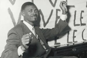 Patrice_Lumumba_(*02.07.1925-17.01.1961+,_ermordet),_Politiker,_Kongo;_der_erste_Ministerpräsident_der_Demokratischen_Republik_Kongo.___Verhandlungen_über_die_Unabhängigkeit_des_Kongos_in_Brüssel:_Lumumba,_der_wenige_Tage_vor_der_Konferenz_aus_dem_Gefängnis_im_Kongo_entlassen_wurde,_zeigt_in_seinem_Hotelzimmer_Journalisten_seine_verbundenen_Handgelenke,_die_von_Handschellen_verletzt_wurden.__Brüssel,_26.01.1960.